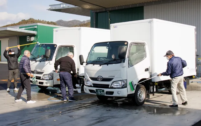 画像：トラックを洗浄するスタッフ
